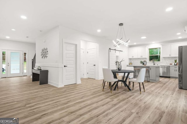 dining area featuring recessed lighting, a barn door, and light wood-style floors