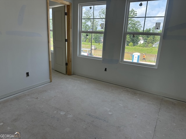 spare room with concrete floors, baseboards, and plenty of natural light