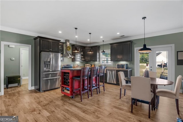 3224 Ware St, Blackshear, GA 31516 - kitchen with appliances with stainless steel finishes, light wood finished floors, wall chimney exhaust hood, a kitchen island, and ornamental molding