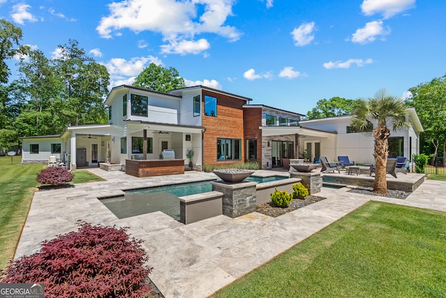 rear view of property with ceiling fan, an outdoor living space with a fire pit, a yard, a patio, and a jacuzzi