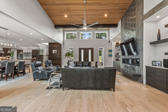 living area with a ceiling fan, a large fireplace, light wood-style floors, a high ceiling, and recessed lighting