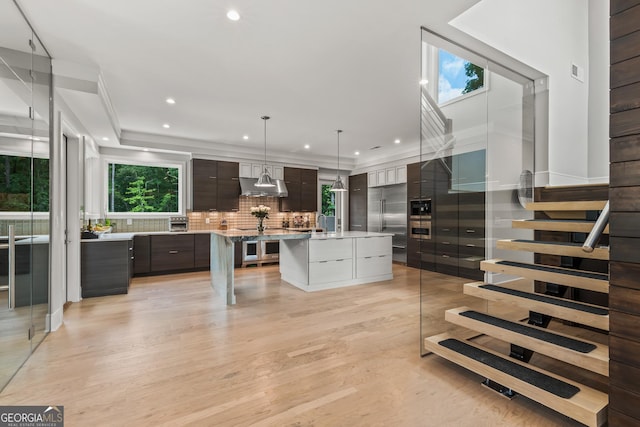 kitchen featuring light countertops, built in fridge, a kitchen bar, under cabinet range hood, and modern cabinets