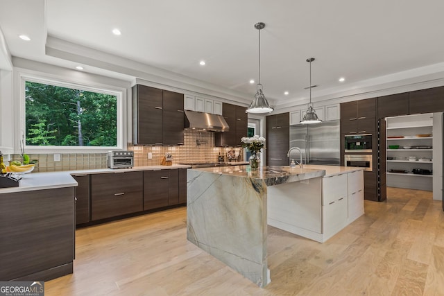 kitchen with dark brown cabinets, appliances with stainless steel finishes, backsplash, under cabinet range hood, and modern cabinets