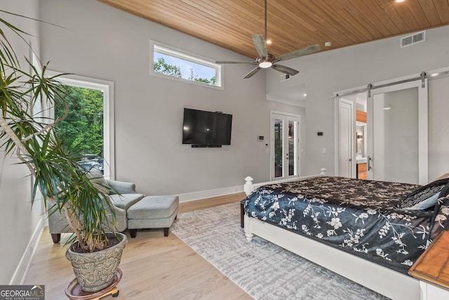 bedroom with visible vents, wood finished floors, baseboards, a barn door, and wood ceiling
