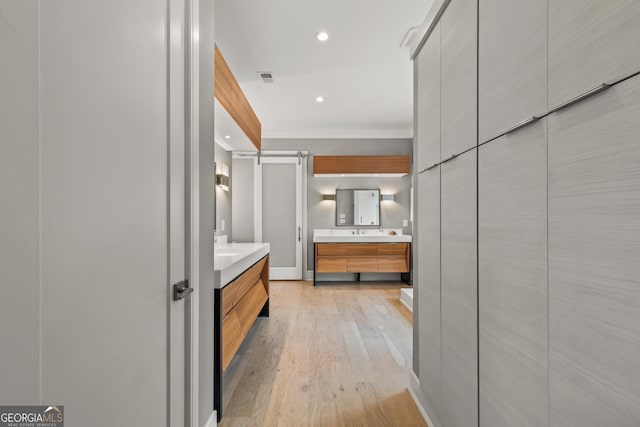 bathroom featuring recessed lighting, visible vents, two vanities, and wood finished floors
