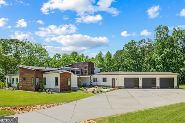 view of front of house featuring stone siding, an attached garage, driveway, and a front yard