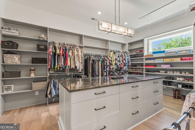 spacious closet with light wood-style floors, attic access, and visible vents