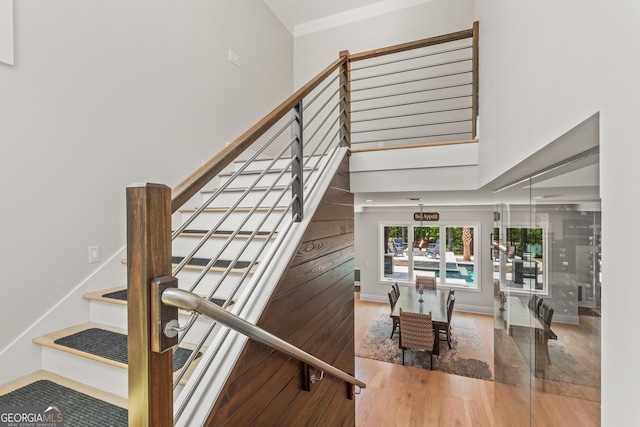 stairs with ornamental molding and wood finished floors