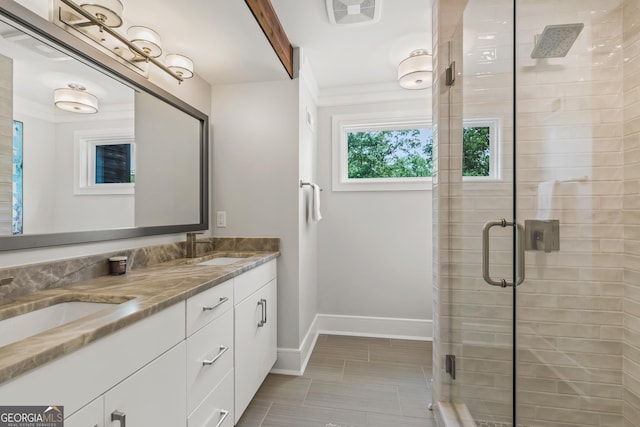 full bathroom with double vanity, baseboards, a shower stall, and a sink