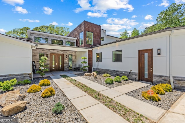 contemporary home featuring french doors and stone siding