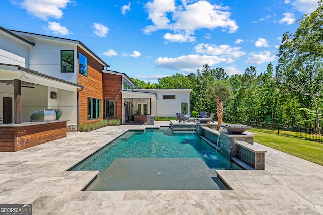 view of swimming pool featuring exterior kitchen, a fenced in pool, a ceiling fan, and a patio area