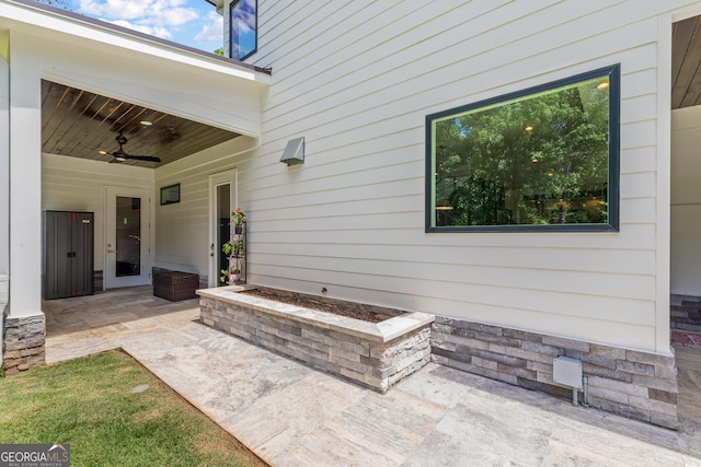 entrance to property featuring stone siding, ceiling fan, and a patio area