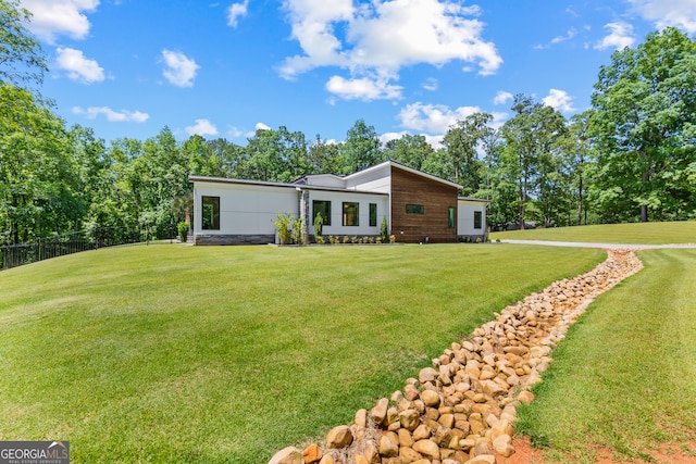 rear view of house with fence and a yard