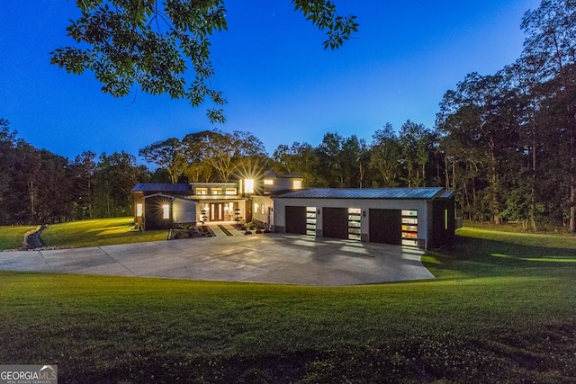 view of front facade with concrete driveway, metal roof, and a front yard