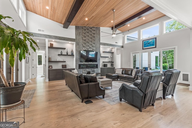 living area featuring beamed ceiling, ceiling fan, plenty of natural light, and a towering ceiling