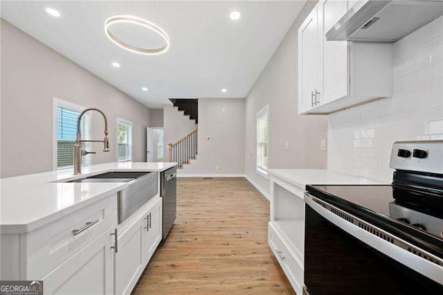 962 Welch St SW, Atlanta, GA 30310 - kitchen with light countertops, under cabinet range hood, white cabinets, light wood-style flooring, and stainless steel appliances