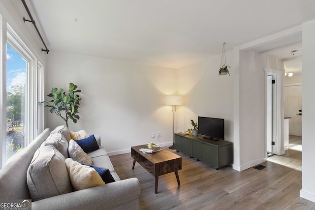 living area featuring baseboards, light wood-style flooring, and visible vents