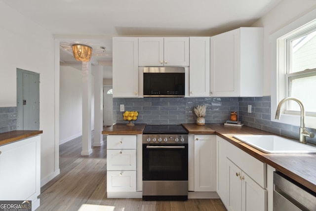 kitchen featuring tasteful backsplash, a sink, white cabinets, light wood-style floors, and stainless steel appliances