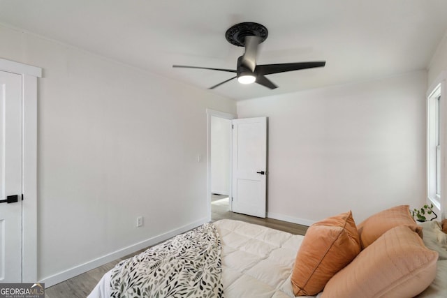 bedroom featuring a ceiling fan, baseboards, multiple windows, and light wood-style flooring