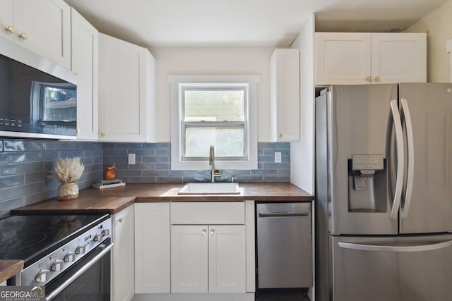 kitchen featuring stainless steel appliances, a sink, butcher block counters, and tasteful backsplash
