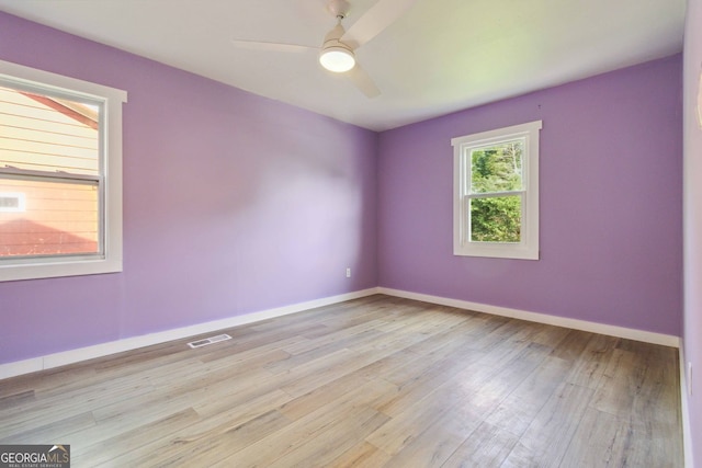 unfurnished room with baseboards, ceiling fan, visible vents, and wood finished floors