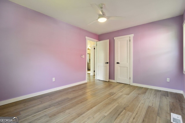 spare room with baseboards, ceiling fan, light wood-type flooring, and visible vents