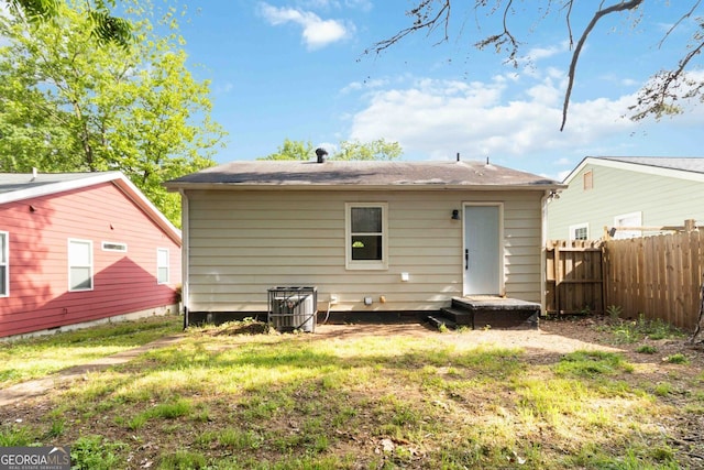 back of property featuring a lawn and fence