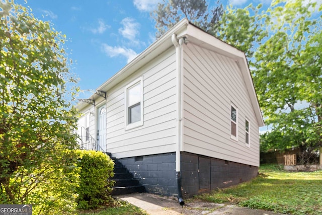 view of side of property featuring crawl space, fence, a yard, and stairway