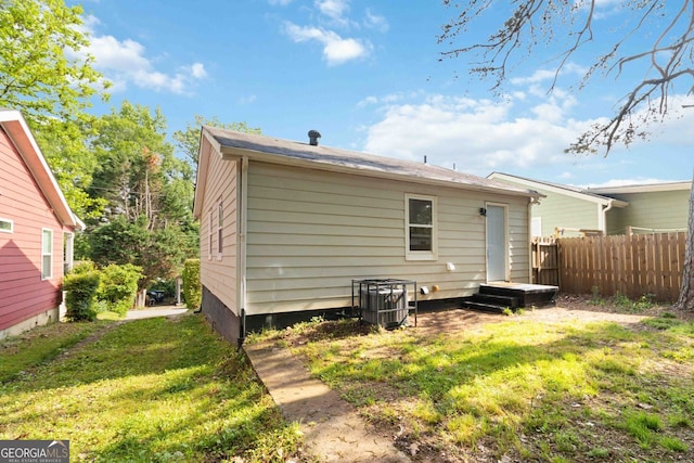 back of property featuring central air condition unit, a yard, and fence