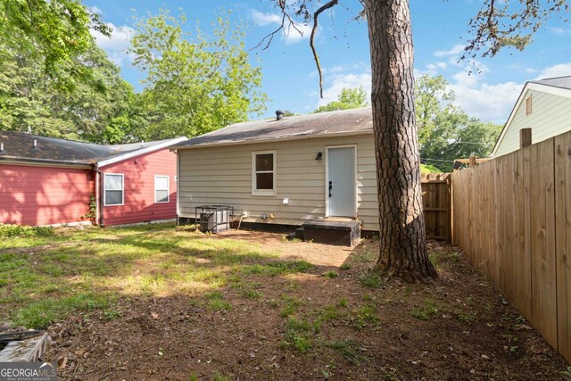 rear view of property with central AC unit and fence