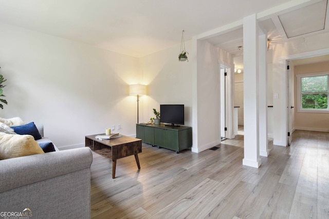 living area with baseboards, light wood-style flooring, and visible vents