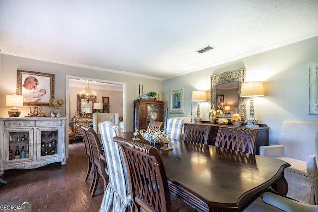 dining room featuring crown molding, a notable chandelier, visible vents, and hardwood / wood-style floors