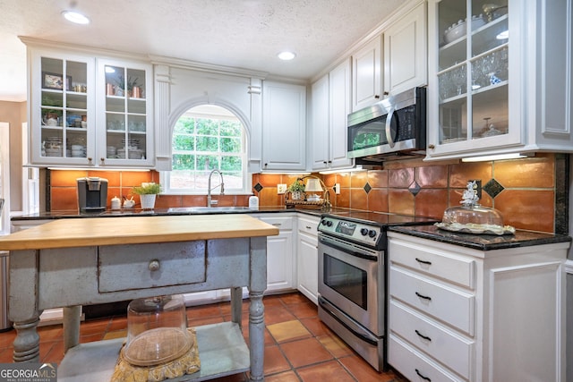 kitchen featuring backsplash, white cabinetry, appliances with stainless steel finishes, and a sink