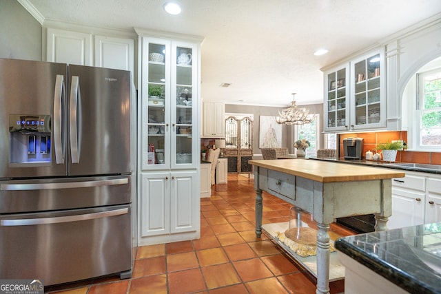 kitchen with wooden counters, light tile patterned floors, stainless steel fridge with ice dispenser, a notable chandelier, and white cabinetry