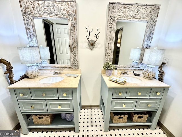 bathroom featuring baseboards, two vanities, and a sink