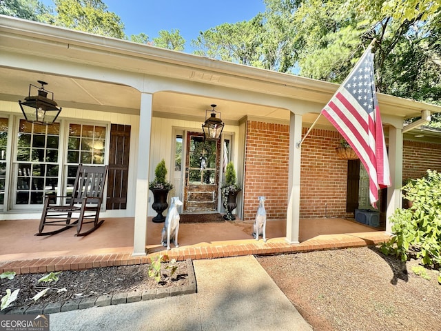 doorway to property with a porch and brick siding