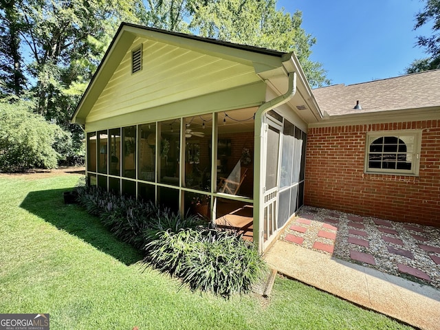 back of property with a lawn, a sunroom, roof with shingles, and brick siding