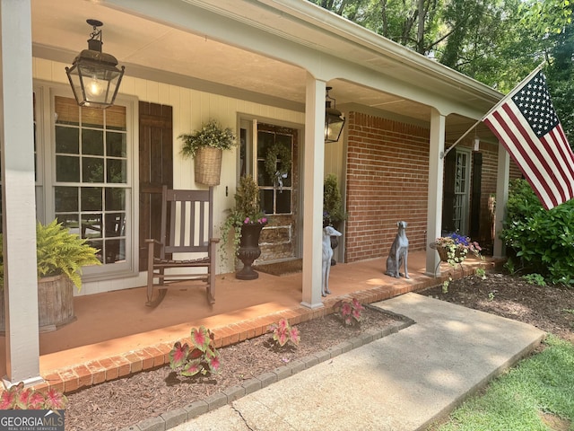 entrance to property featuring a porch and brick siding