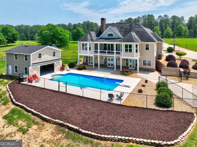 back of property with a patio, a chimney, a balcony, and a fenced backyard