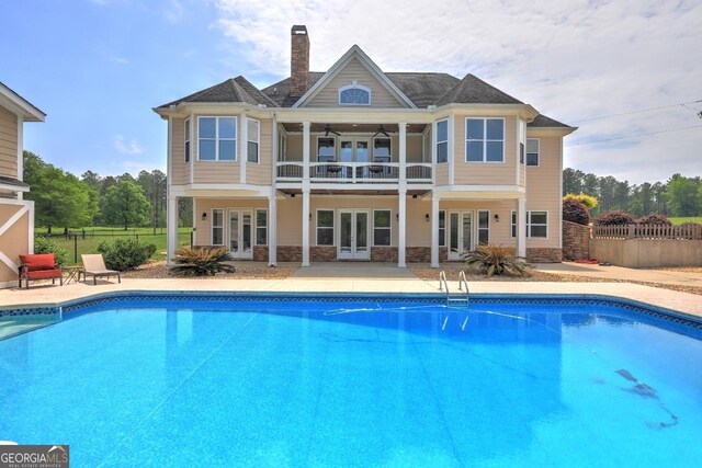 back of house with a fenced in pool, ceiling fan, and french doors