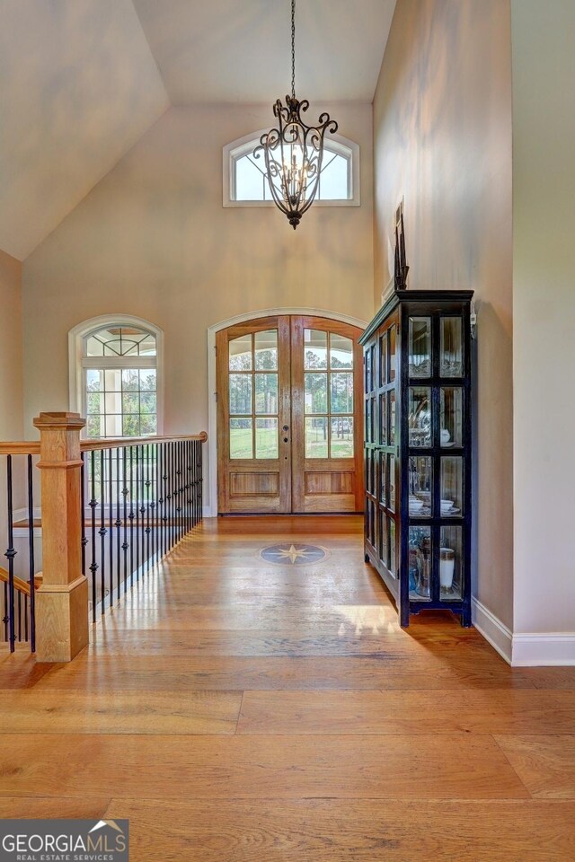 entrance foyer featuring french doors, wood finished floors, a chandelier, and a healthy amount of sunlight