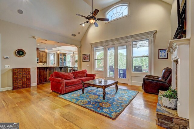 living area featuring high vaulted ceiling, plenty of natural light, a ceiling fan, and light wood-style flooring