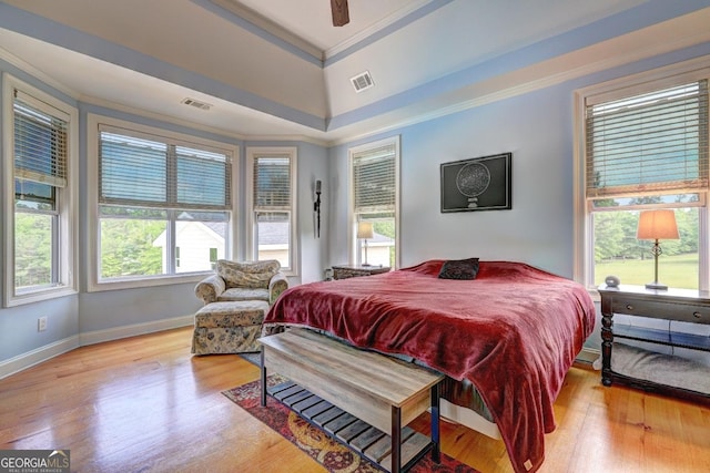 bedroom with visible vents, crown molding, and wood finished floors