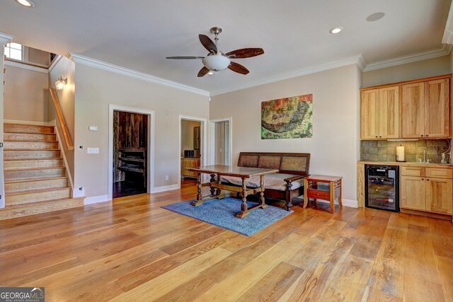 dining area with stairs, ornamental molding, light wood finished floors, and wine cooler