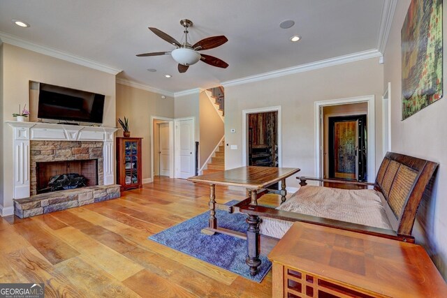 interior space with crown molding, a fireplace, light wood-style floors, stairway, and a ceiling fan