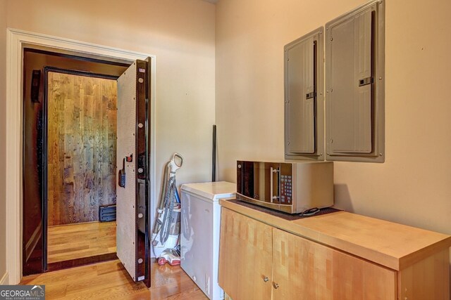 laundry room featuring electric panel and light wood-type flooring