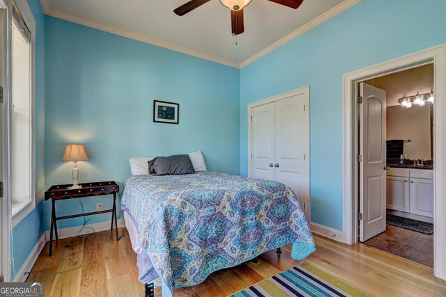 bedroom with crown molding, baseboards, wood finished floors, and a closet