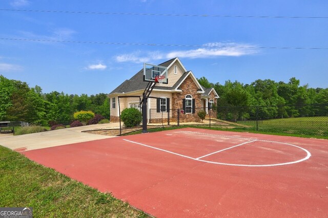 view of basketball court featuring fence and basketball hoop