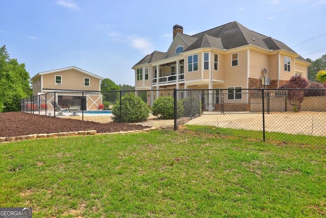 back of property with a lawn, fence, a chimney, and a fenced in pool