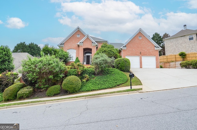 view of front facade with a garage, fence, concrete driveway, and brick siding